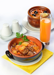 Still life of setout table with soup and meat in ceramic pots an