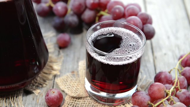 Fresh made Grape Juice in a glass (wooden background)