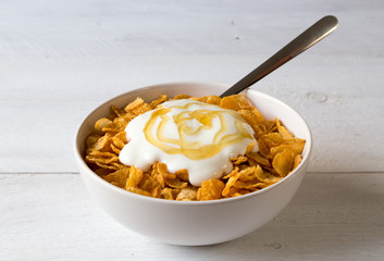 Cornflakes in einer Schale mit Joghurt und Honig.