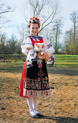 The smiling girl in folk costume with little lamb