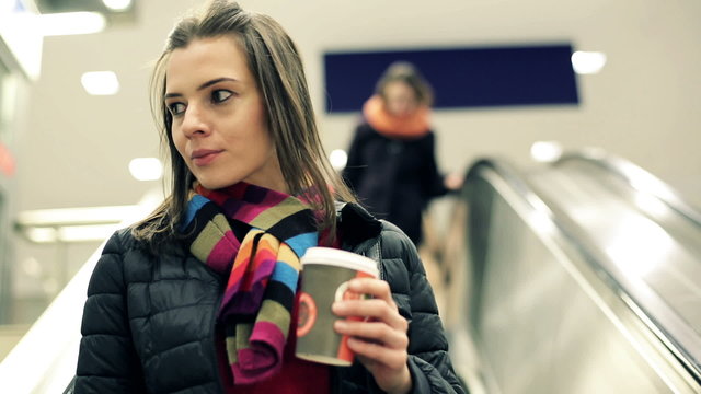 Woman on escalator drinking coffee
