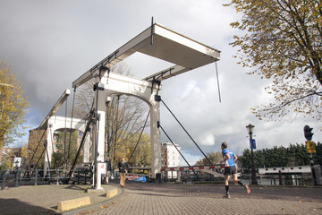 Fototapeta na wymiar man running over old wooden bridge in amsterdam
