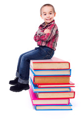 Little boy sitting on stacked colorful books