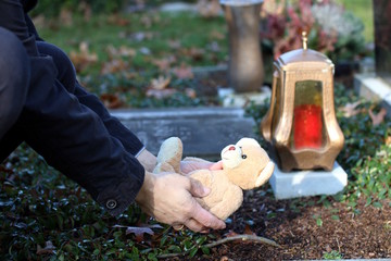 Angehöriger legt Teddy auf Grab von Verstorbenen