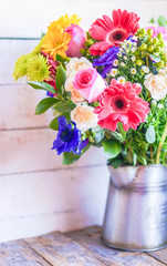 Colorful bouquet of spring flowers in vintage vase on rustic woo