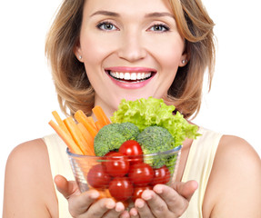 Portrait of a young smiling woman with a plate of vegetables.