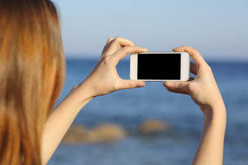 Back view of a woman taking photo with a smart phone camera