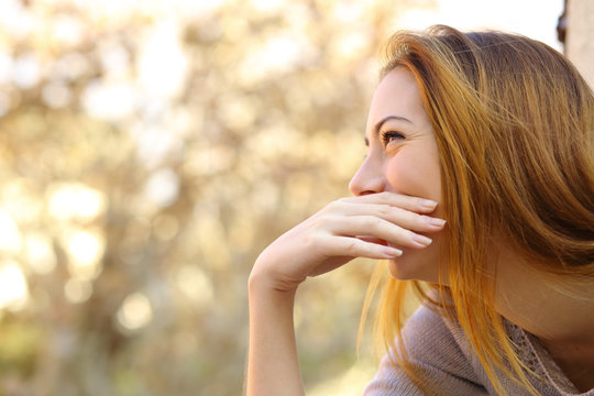 Happy woman laughing covering her mouth with a hand