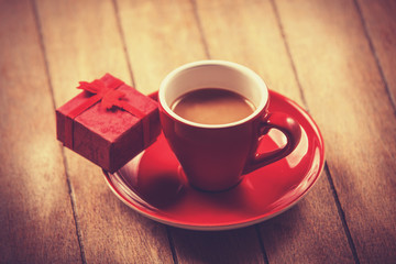 Red cup of the coffee and little gift.