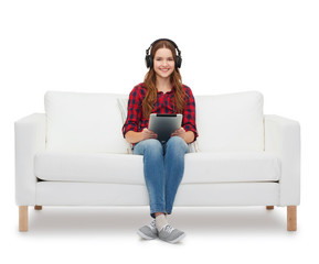 Obraz na płótnie Canvas girl sitting on sofa with headphones and tablet pc