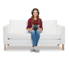 girl sitting on sofa with headphones and tablet pc