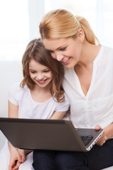 smiling mother and little girl with laptop at home