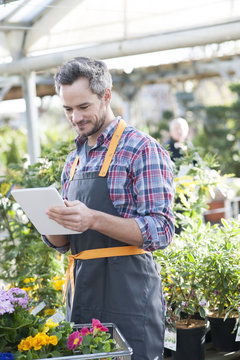 Professional gardener using a digital tablet in a garden center