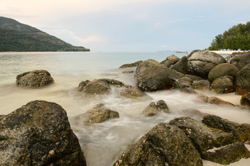 beach with rocks and waves; sunset background
