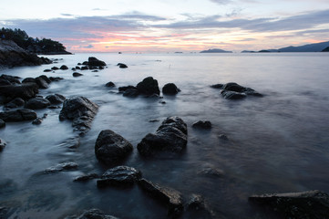 Obraz premium beach with rocks and waves; sunset background