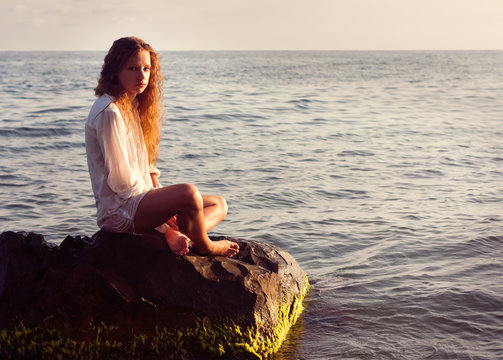 girl sitting on a rock sea