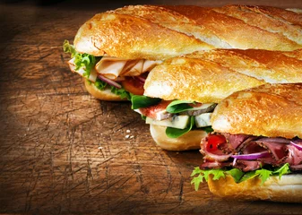 Foto auf Leinwand Three tasty baguettes with savory fillings © exclusive-design