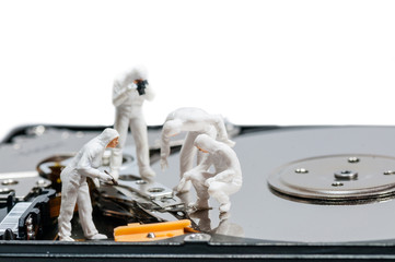 Group of criminologists inspecting broken hard rive