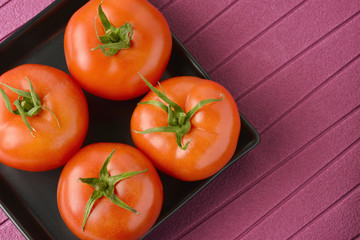 Fresh tomatoes placed in a black ceramic plate