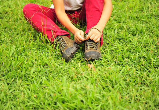 hiker tying shoelace on grass