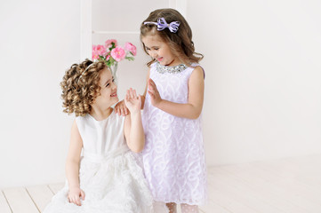 Cute little girls in white dresses talking.