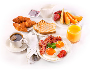 Breakfast with fried eggs, coffee,  juice, croissant and fruits