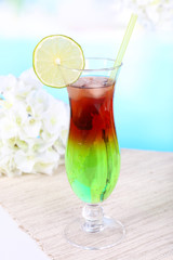 Glass of cocktail on table on light blue background