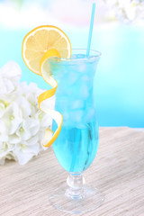 Glass of cocktail on table on light blue background