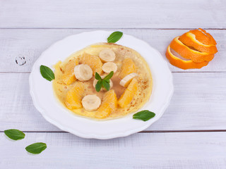 Pancake on a plate with fruits on a  wooden table