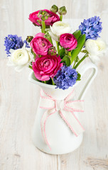ranunculus and hyacinth flowers in a pitcher