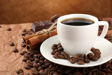 Coffee beans and cup of coffee on table on brown background