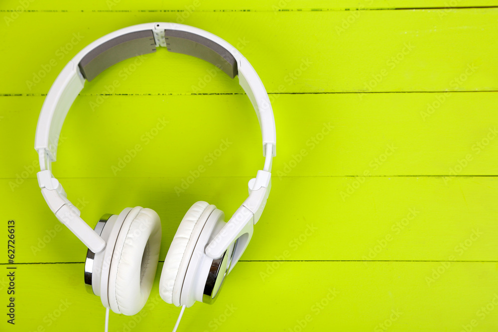 Wall mural White headphones on wooden table close-up