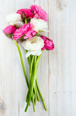 pink and white ranunculus flowers on woode surface