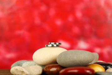 Wedding rings on rocks on red background