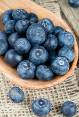 fresh blueberries in a wooden spoon over wooden table