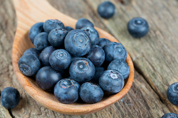 fresh blueberries in a wooden spoon over wooden table