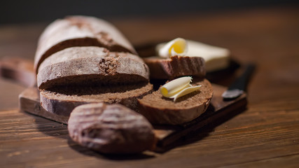 Bread with butter at the woodent table in low-light style
