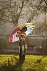 sad boy with colorful rainbow umbrella in park