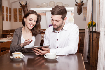 Young woman and man using tablet in coffee shop