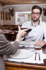 Smiling young man clinking glasses with his girlfriend