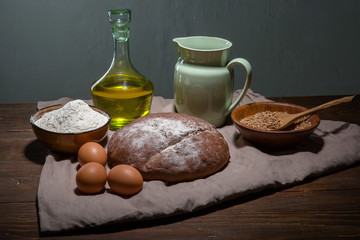 Still life photo of bread and grain with milk and eggs at the wo