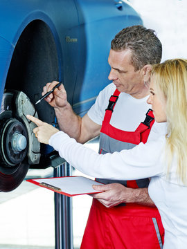 Car mechanic explains something to a customer
