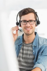 Portrait of a smiling man with headset using computer