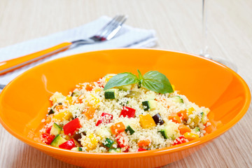 Couscous with vegetables in orange dish