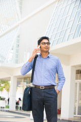 indian business male on a phone with office background