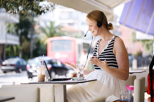 Laughing woman wearing a headset in outdoor cafe