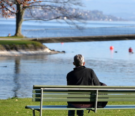homme de dos  lisant au bord du lac