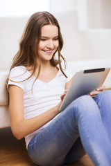 smiling teenage girl with tablet pc at home