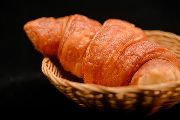 basket of fresh croissant on black background