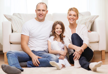 parents and little girl sitting on floor at home